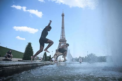 Personas se zambullen en la fuente del Trocadero, frente a la Torre Eiffel, para aliviar el calor