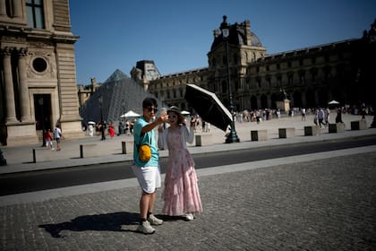 Turistas se protegen del sol con un paraguas durante la ola de calor en París