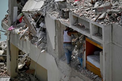 Un hombre rebusca entre los escombros de un edificio derrumbado tratando de recuperar sus pertenencias tras un terremoto en Catia La Mar