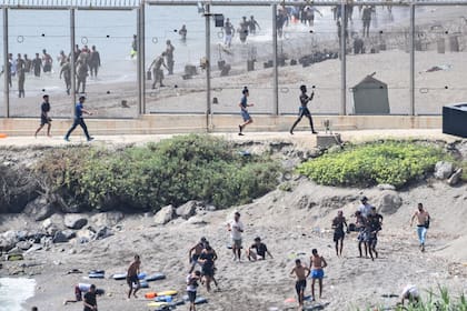 Un grupo de migrantes avanza por la costa tras cruzar desde el vecino Marruecos hacia Ceuta, el enclave español en el norte de África. Más de 1500 migrantes han llegado a Ceuta en la última semana, la mayoría a nado, según las autoridades españolas